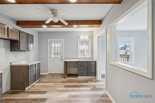 kitchen with dark brown cabinetry, sink, light hardwood / wood-style floors, and beamed ceiling