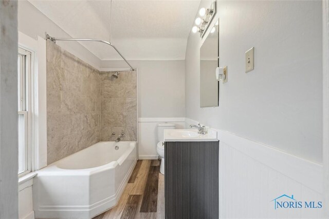 full bathroom with wood-type flooring, toilet, tiled shower / bath combo, and vanity