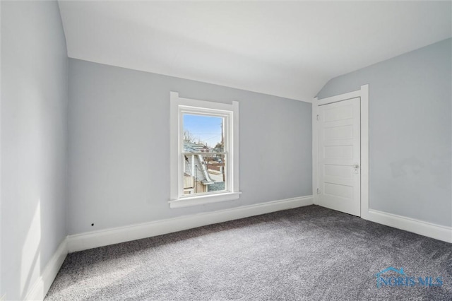 carpeted spare room featuring vaulted ceiling