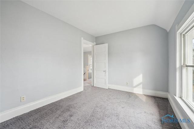 carpeted empty room featuring lofted ceiling