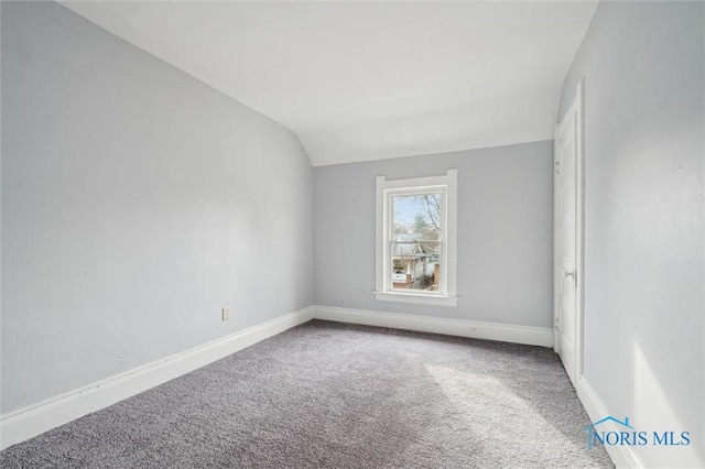 carpeted empty room with lofted ceiling