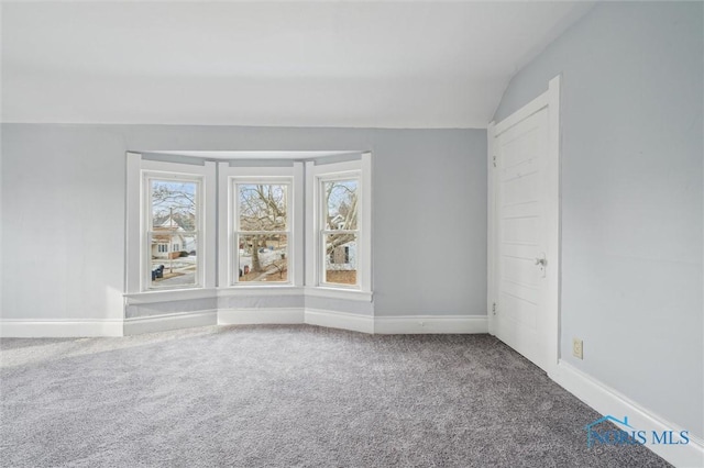 carpeted spare room with lofted ceiling