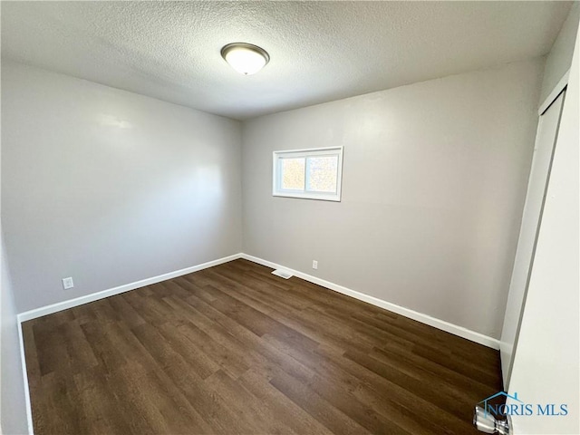 empty room featuring dark hardwood / wood-style flooring and a textured ceiling