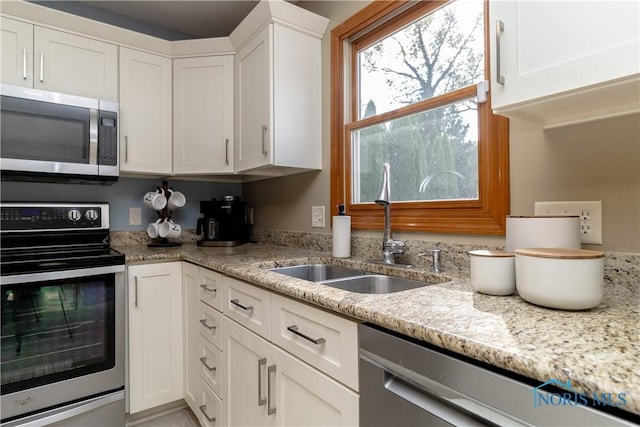 kitchen featuring appliances with stainless steel finishes, light stone countertops, sink, and white cabinets