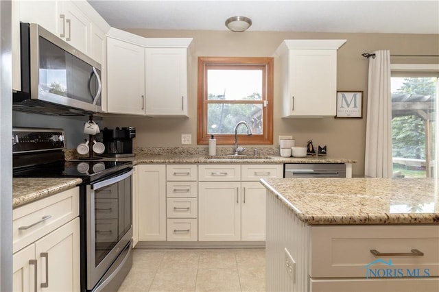 kitchen featuring sink, stainless steel appliances, light stone counters, a wealth of natural light, and white cabinets