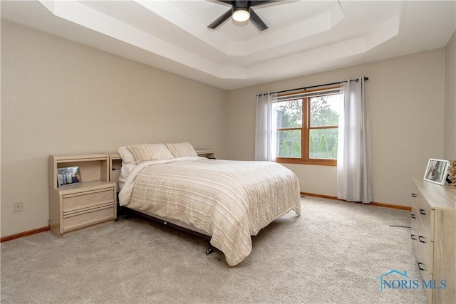 carpeted bedroom with a tray ceiling and ceiling fan