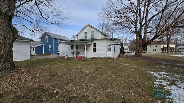 rear view of property with covered porch and a lawn