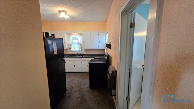 kitchen featuring black refrigerator, white cabinetry, range, dark carpet, and a textured ceiling