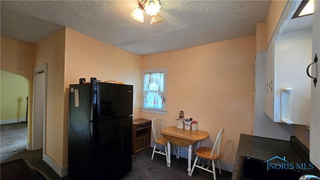 kitchen featuring black refrigerator, dark carpet, and a textured ceiling