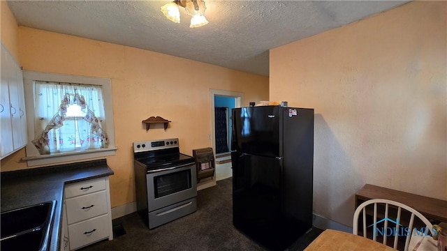 kitchen with electric stove, sink, black refrigerator, white cabinetry, and a textured ceiling