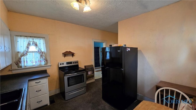 309 Appian Ave, Napoleon, OH 43545 - kitchen featuring a textured ceiling, stainless steel electric range oven, dark carpet, a sink, and freestanding refrigerator