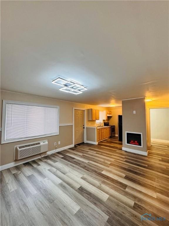 unfurnished living room featuring a wall unit AC and light wood-type flooring