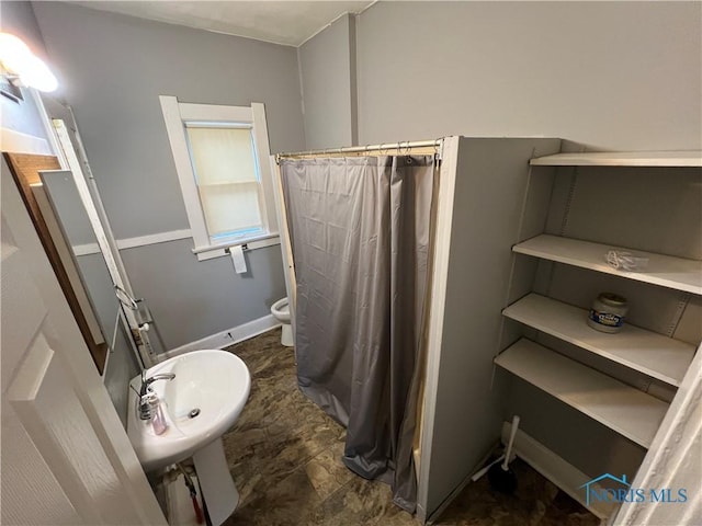 bathroom featuring walk in shower, sink, and toilet