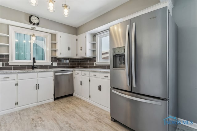 kitchen featuring stainless steel appliances, white cabinetry, hanging light fixtures, and sink