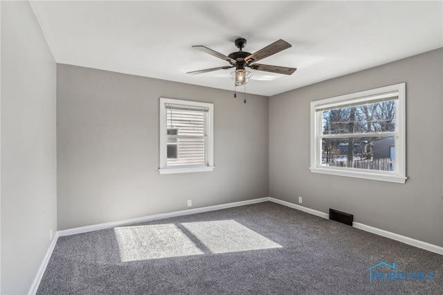 empty room with a wealth of natural light, ceiling fan, and carpet