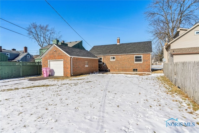 snow covered rear of property with a garage