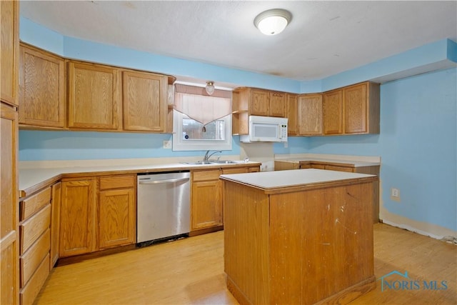 kitchen featuring a center island, dishwasher, sink, and light wood-type flooring