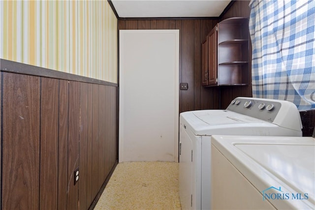 clothes washing area featuring washing machine and clothes dryer and wooden walls