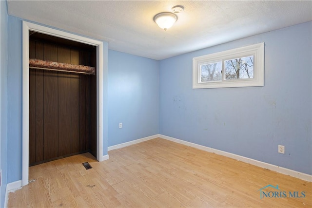 unfurnished bedroom featuring light hardwood / wood-style floors, a closet, and a textured ceiling