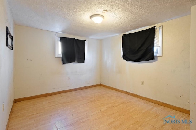 empty room with light hardwood / wood-style flooring and a textured ceiling