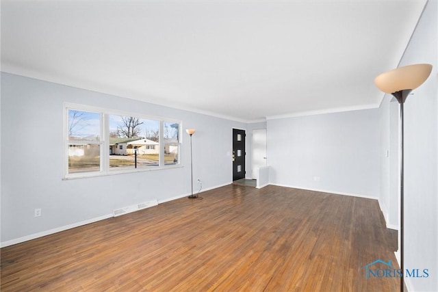 unfurnished living room featuring dark hardwood / wood-style flooring and crown molding