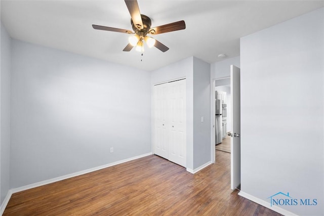 unfurnished bedroom with dark wood-type flooring, a closet, and ceiling fan