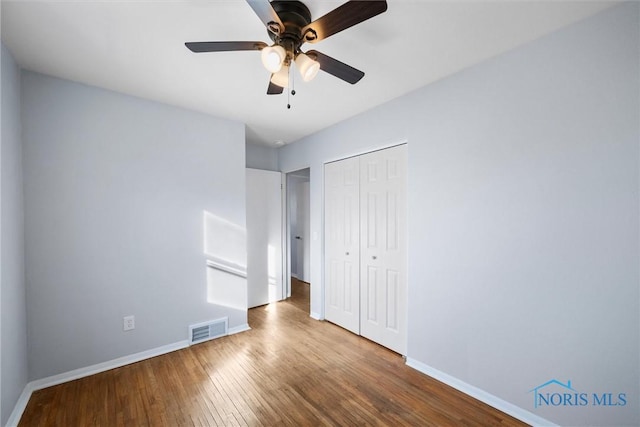 unfurnished bedroom featuring hardwood / wood-style floors, a closet, and ceiling fan