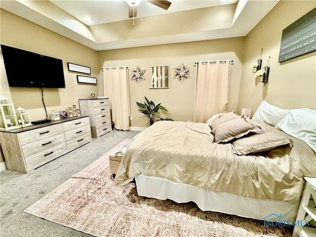 bedroom featuring a tray ceiling, carpet floors, and ceiling fan