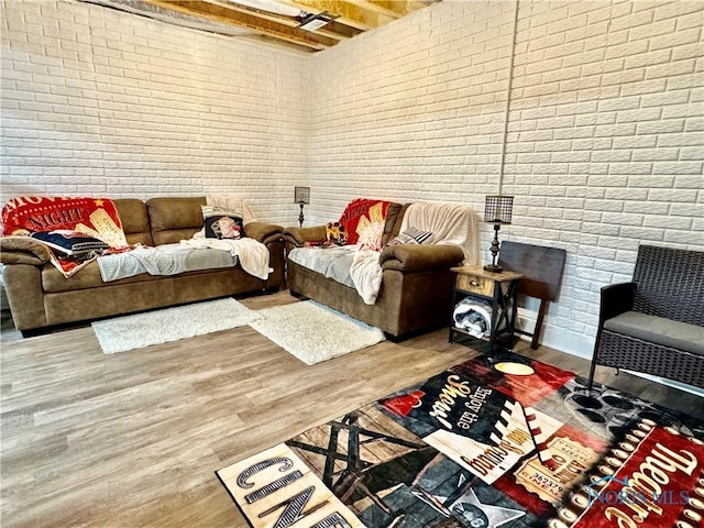 living room with hardwood / wood-style flooring and brick wall