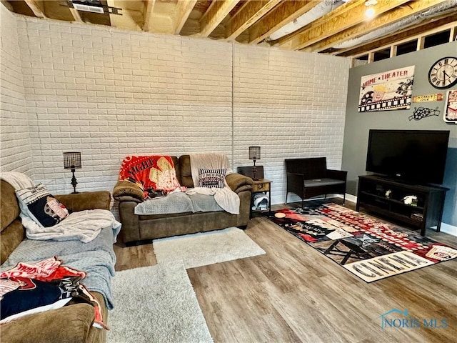 living room with brick wall and hardwood / wood-style floors