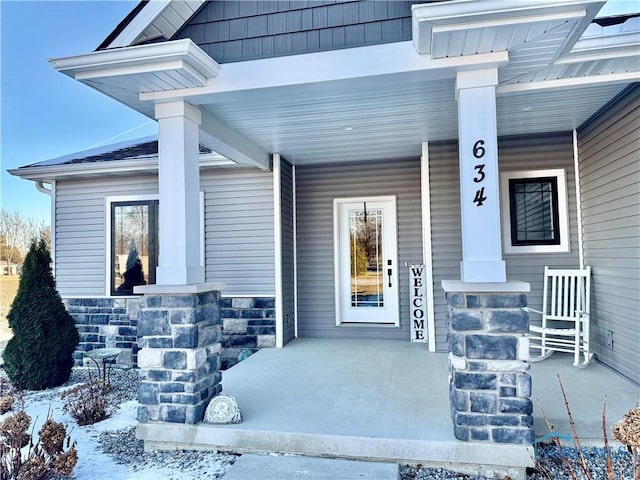 snow covered property entrance featuring covered porch