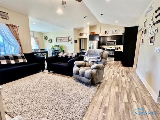 living room with vaulted ceiling, ceiling fan, and light wood-type flooring