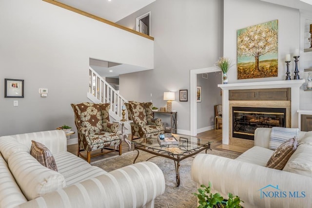 living room with a towering ceiling, a fireplace, and light hardwood / wood-style floors