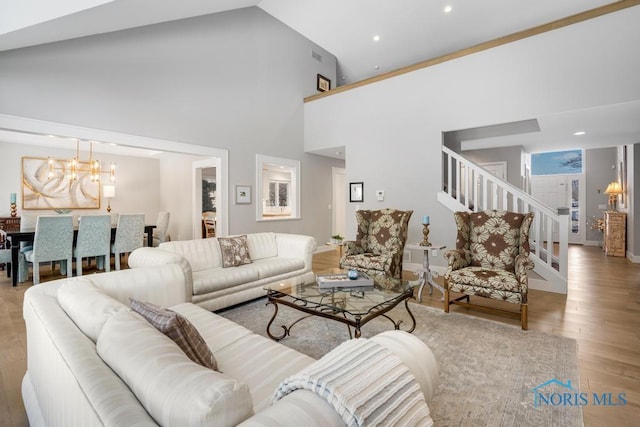 living room featuring high vaulted ceiling, a chandelier, and light wood-type flooring