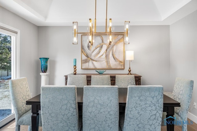 dining area featuring a notable chandelier, a tray ceiling, wood-type flooring, and vaulted ceiling