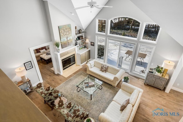 living room with ceiling fan, hardwood / wood-style floors, and high vaulted ceiling