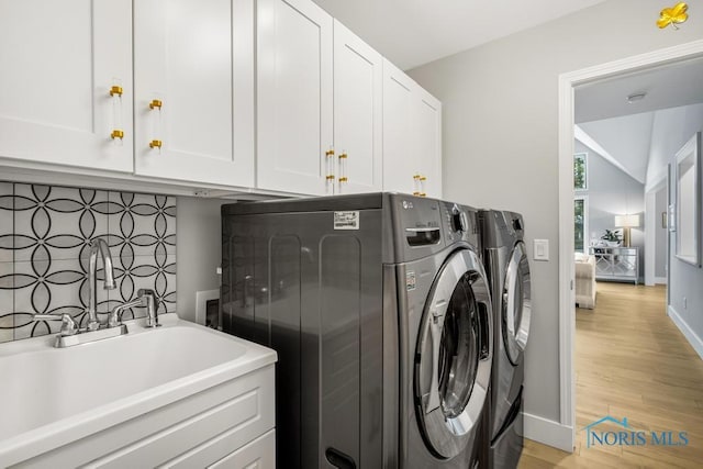 laundry room featuring cabinets, sink, separate washer and dryer, and light hardwood / wood-style floors