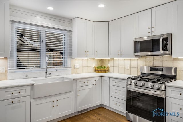 kitchen featuring white cabinetry, stainless steel appliances, sink, and backsplash