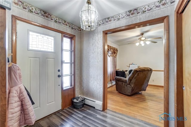 entrance foyer with hardwood / wood-style flooring, a baseboard radiator, and ceiling fan with notable chandelier