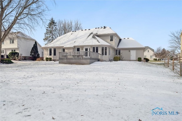 snow covered back of property featuring a deck