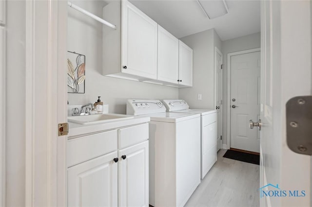 clothes washing area with cabinets, separate washer and dryer, sink, and light hardwood / wood-style flooring