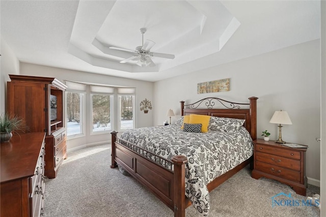 carpeted bedroom featuring ceiling fan and a raised ceiling