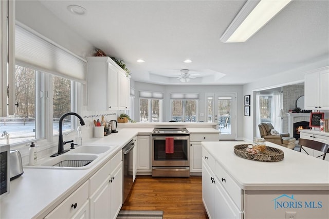 kitchen with dark wood-type flooring, sink, ceiling fan, stainless steel appliances, and white cabinets