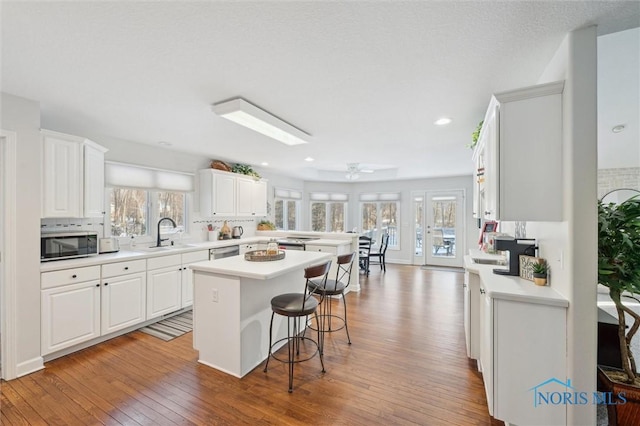 kitchen with stainless steel appliances, white cabinetry, a center island, and a kitchen breakfast bar