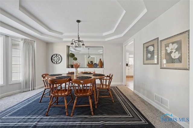 carpeted dining space with a healthy amount of sunlight and a tray ceiling