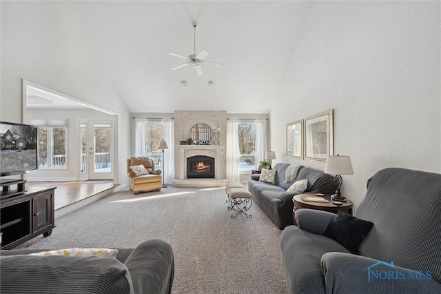 living room with a brick fireplace, high vaulted ceiling, ceiling fan, and carpet flooring