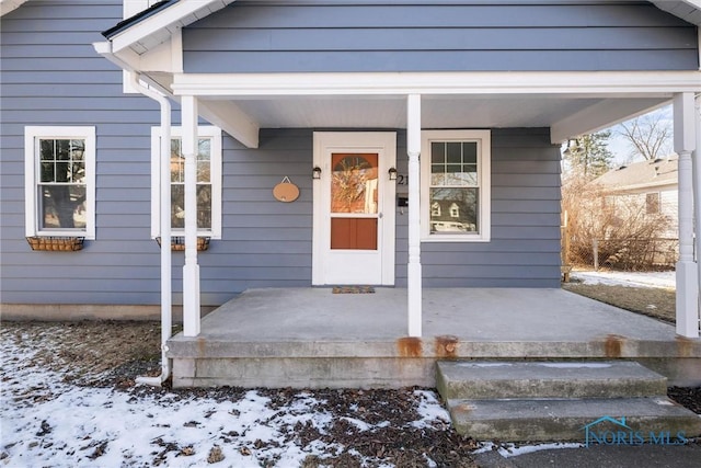 snow covered property entrance featuring a porch