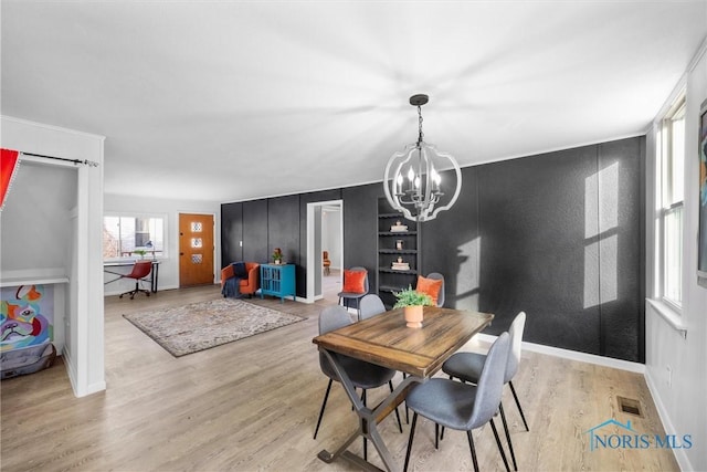 dining area featuring a notable chandelier, light wood-type flooring, and built in shelves