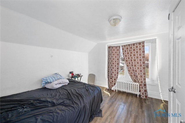 bedroom featuring hardwood / wood-style flooring, radiator heating unit, and vaulted ceiling