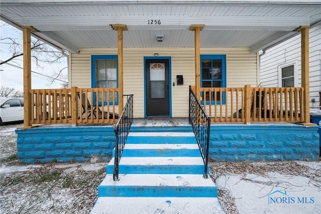 snow covered property entrance with covered porch